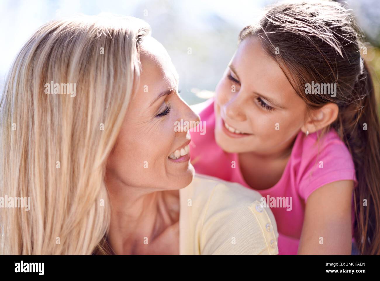 Ti voglio bene. Una madre sorridente con la figlia sulla schiena mentre all'aperto. Foto Stock