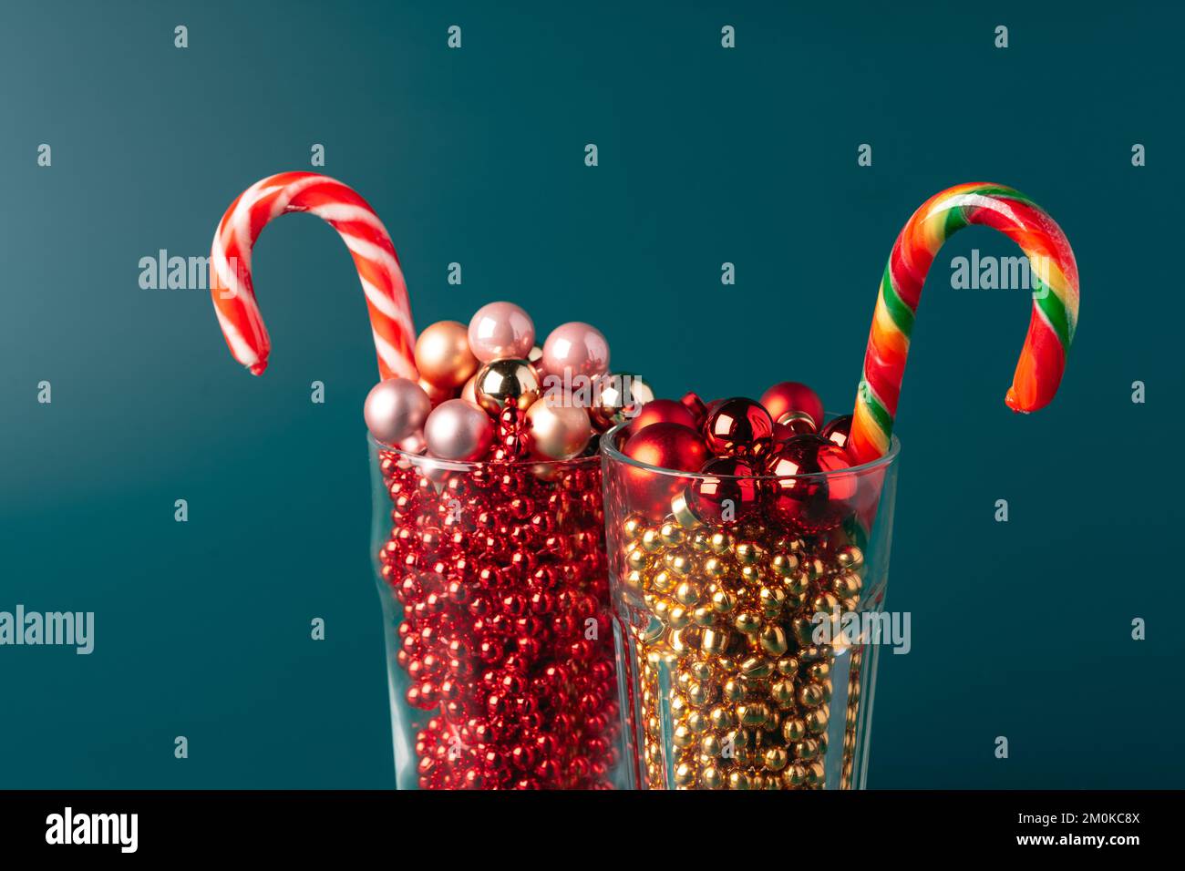Bicchieri di vetro con decorazioni natalizie su sfondo verde scuro Foto Stock