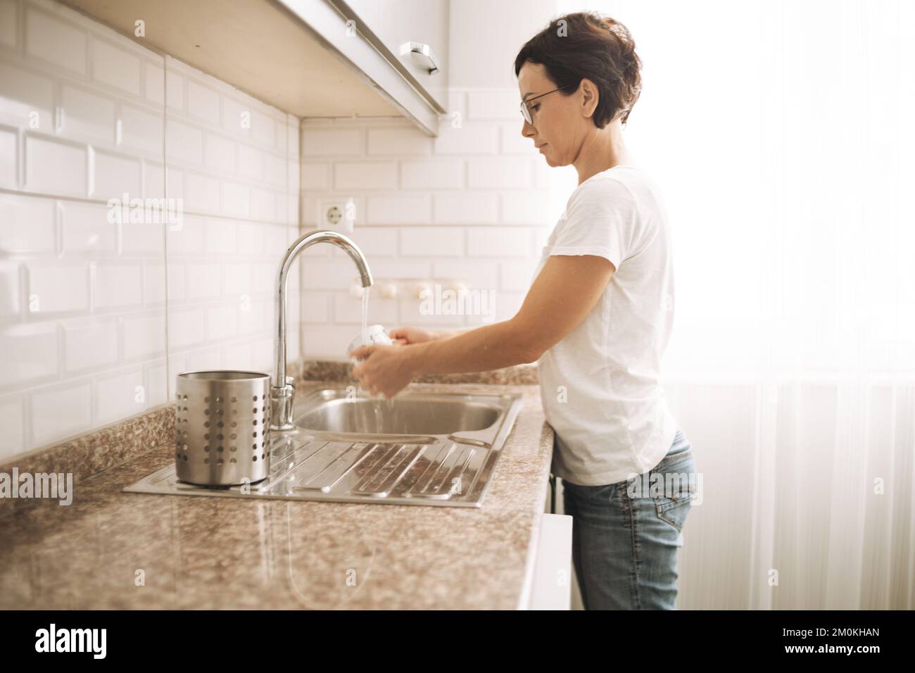 Donna lavaggio piatti. Madre fa rutine lavori di casa Foto Stock