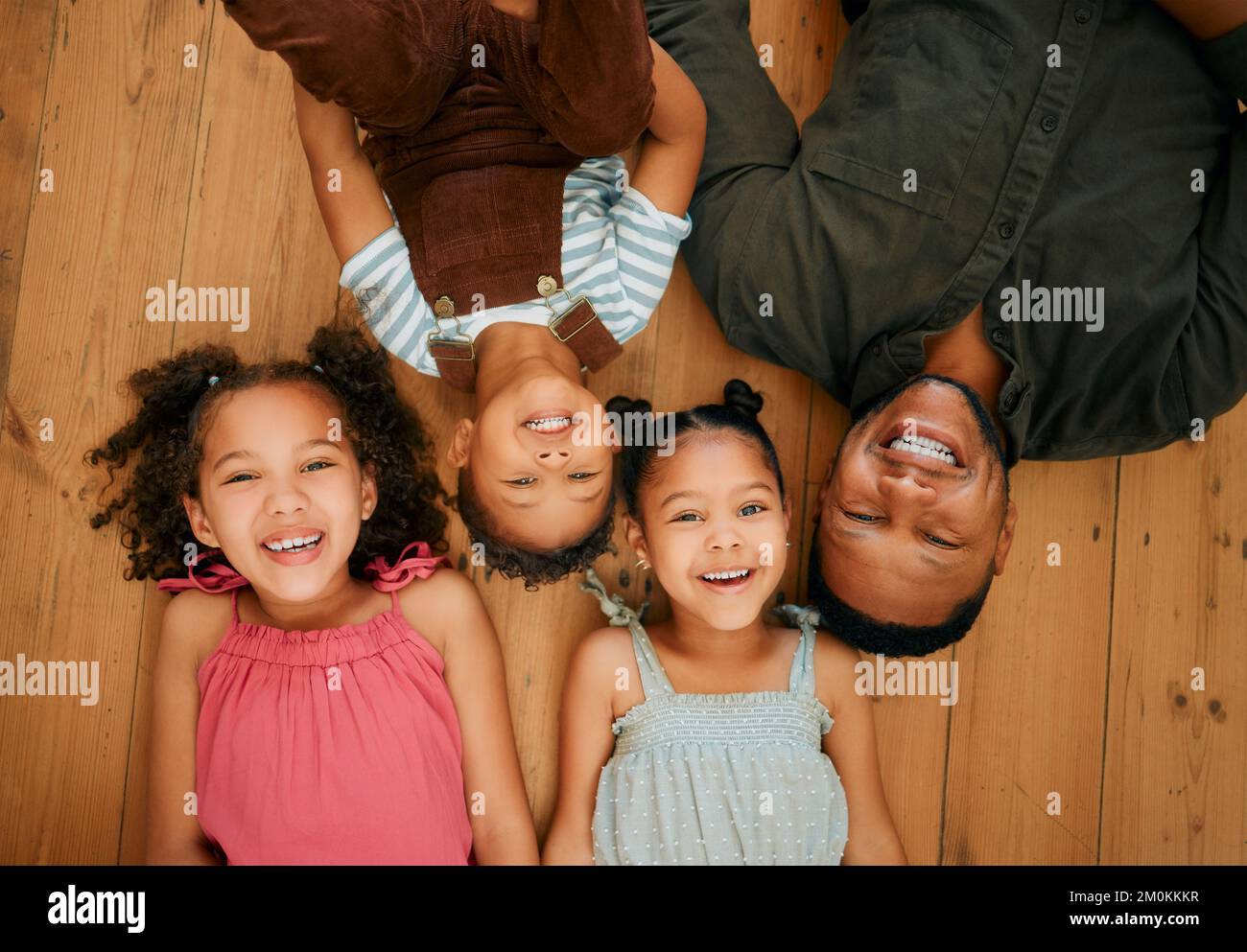 Una felice famiglia di corse miste di quattro persone che si rilassano e sdraiati insieme sul piano lounge. Amorevole nero singolo genitore legame con i suoi figli mentre è Foto Stock