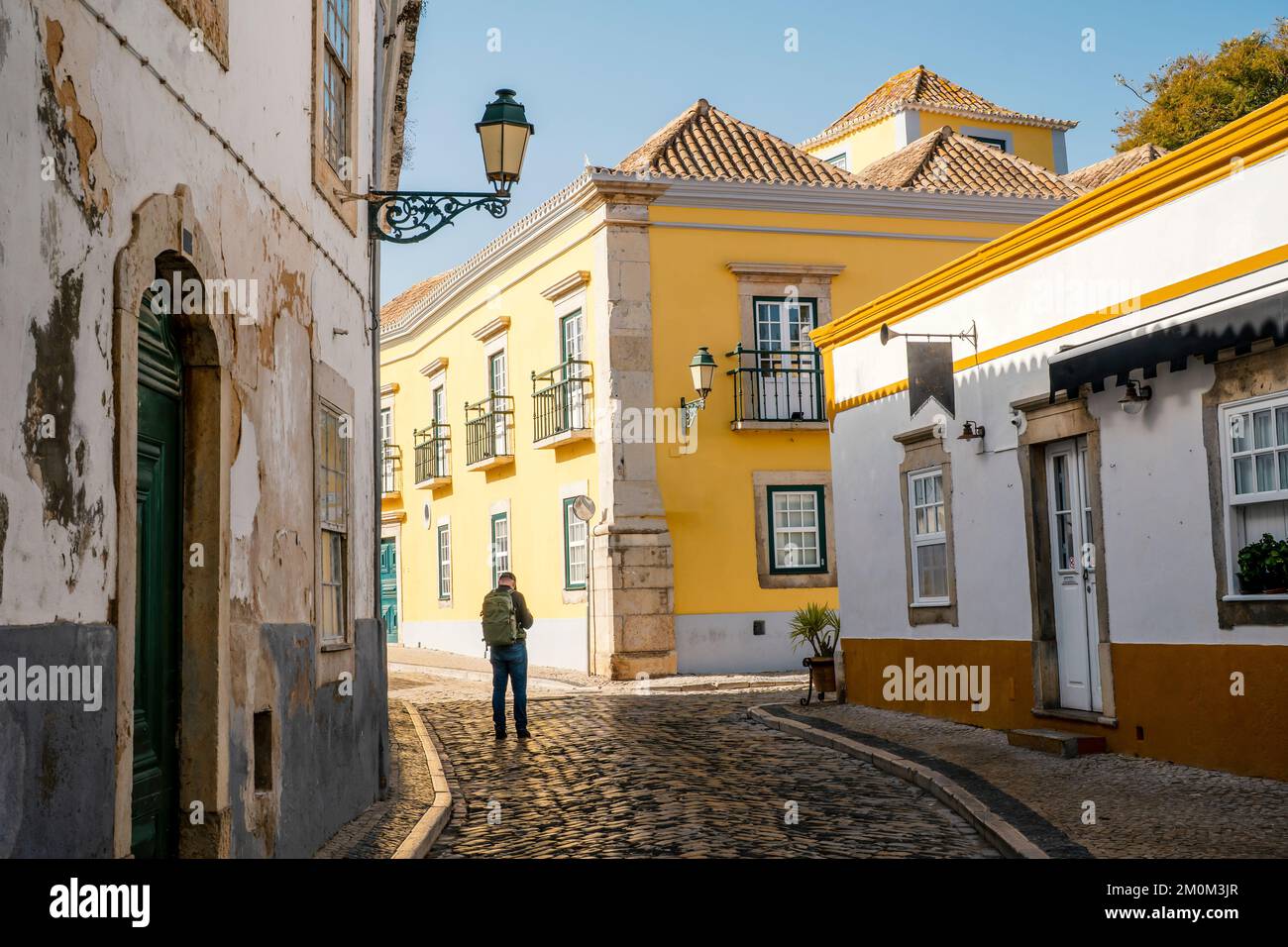 Un turista con zaino alla scoperta di Faro, capitale dell'Algarve, Portogallo Foto Stock