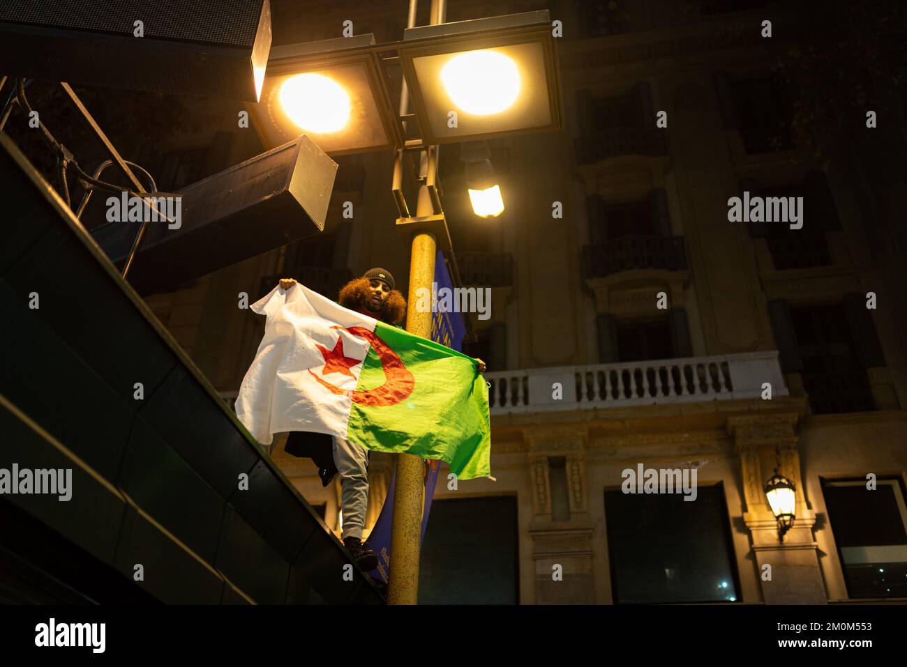 Barcellona, Spagna. 06th Dec, 2022. Un uomo celebra la vittoria della squadra di calcio del Marocco sulla Spagna nel centro della città dopo la partita di calcio con la bandiera algerina. In una vittoria a sorpresa, la squadra marocchina ha battuto la Spagna alle penalità, passando ai quarti di finale, dove affronterà il Portogallo, per la prima volta nella sua storia. (Foto di Davide Bonaldo/SOPA Images/Sipa USA) Credit: Sipa USA/Alamy Live News Foto Stock