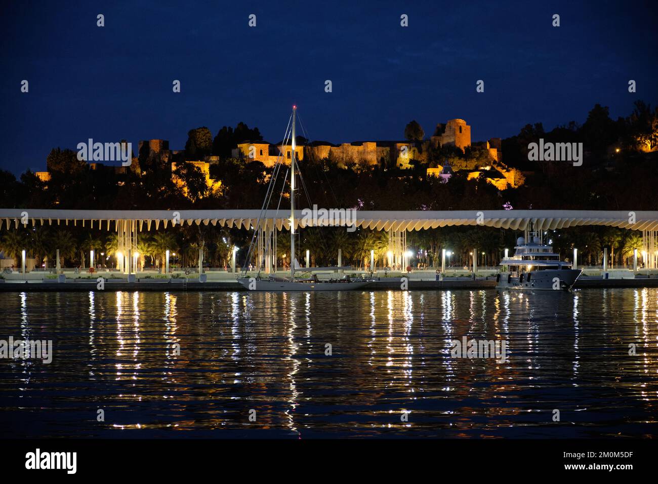 Málaga, Spagna. Vista dal porto. Muelle dos e l'Alcazaba di notte Foto Stock