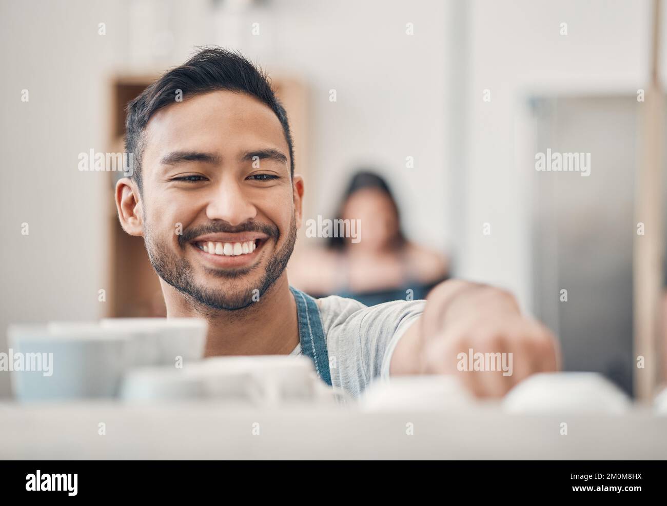 Un cameriere Happy hispanic che usa una macchina per il caffè per preparare una bevanda calda in un bar. Buon barista preparare una bevanda calda per servire i clienti in un Foto Stock