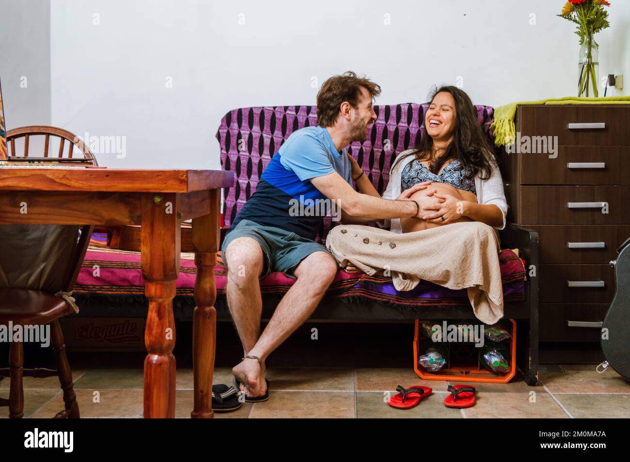 Una coppia di adulti eterosessuali incinta di argentino caucasico e donna brasiliana sorridono felice e toccano il ventre sentendo i movimenti del th Foto Stock