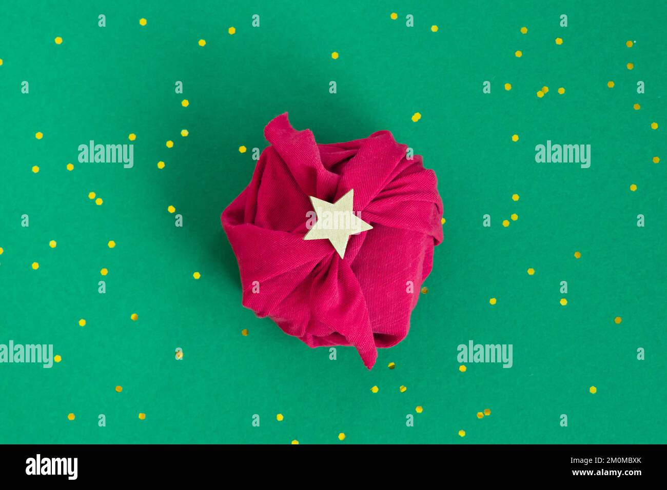 Carta regalo senza confezione tecnica Furoshiki. Tessuto Viva magenta su sfondo verde. Piano di giacitura, scatola di presentazione, vista dall'alto. Natale, San Valentino, nuovo Foto Stock