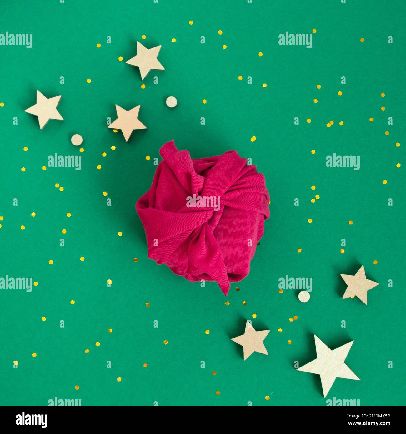 Carta regalo senza confezione tecnica Furoshiki. Tessuto Viva magenta su sfondo verde. Piano di giacitura, scatola di presentazione, vista dall'alto. Natale, San Valentino, nuovo Foto Stock