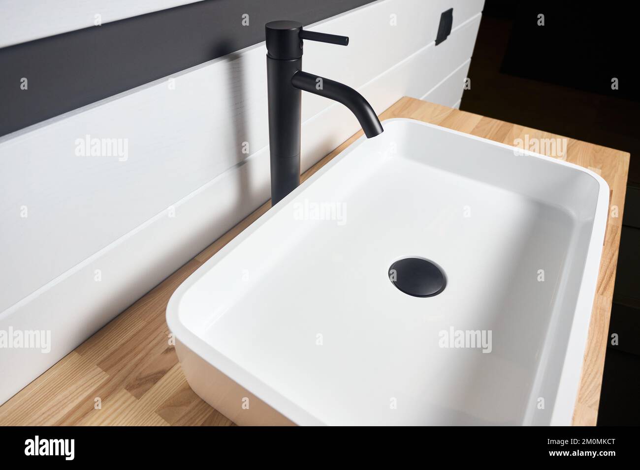 Interno del bagno con lavabo quadrato in ceramica e rubinetto nero. Bagno interno lavabo con legno frassino massiccio lamelato sotto vernice Foto Stock