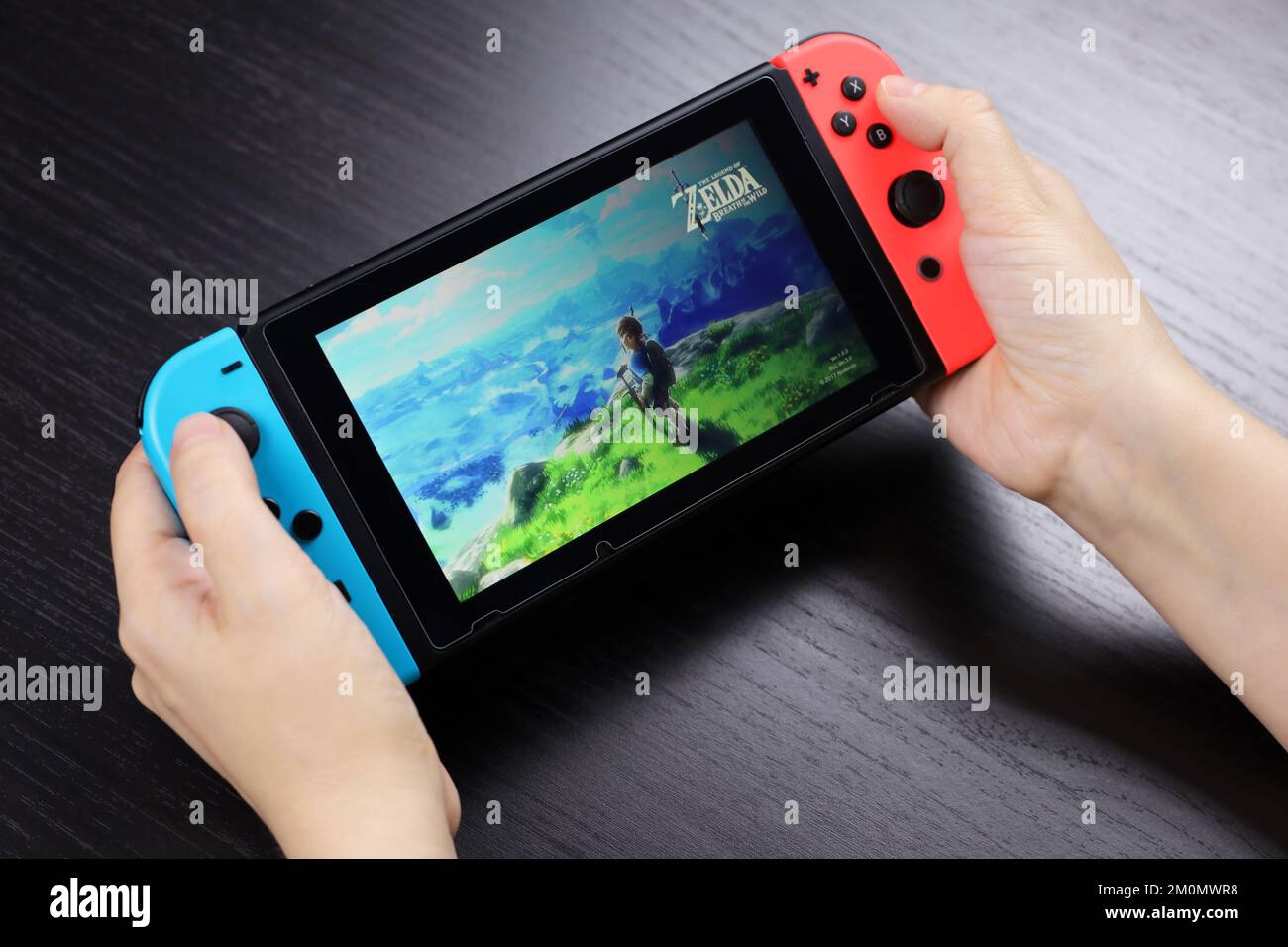 Ragazza che gioca il gioco Legend of Zelda su console Nintendo Switch in modalità portatile, messa a fuoco selettiva su uno schermo Foto Stock