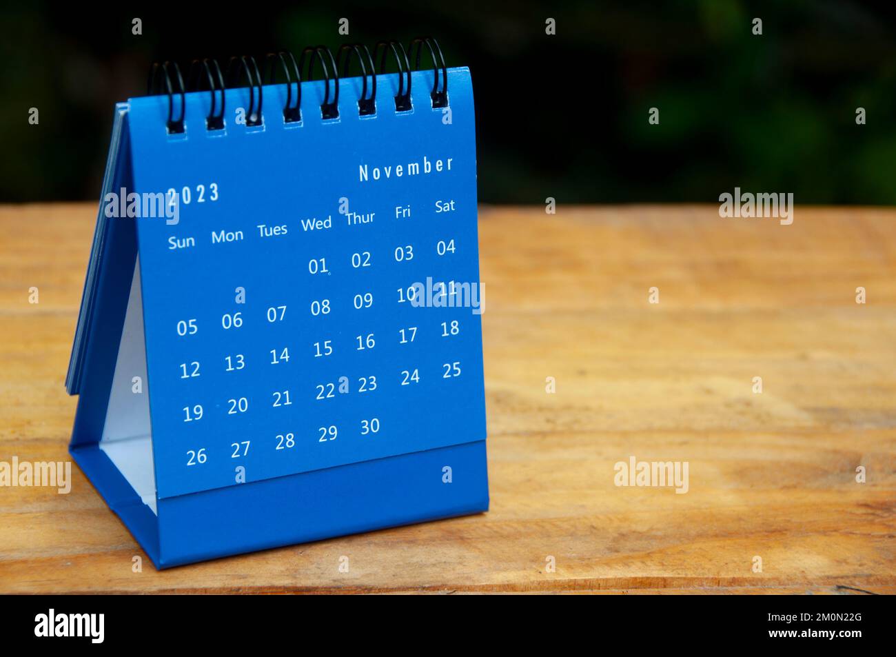 Novembre 2023 scrivania blu calendario su sfondo tavolo in legno con spazio personalizzabile per il testo. Foto Stock