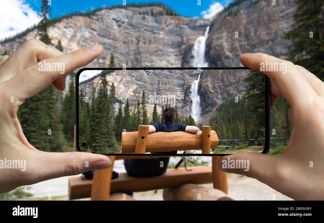 Tourist scattare una foto con un telefono cellulare delle cascate di Takakkaw, Canada. Foto Stock