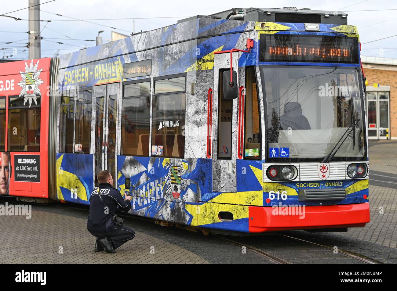 07 dicembre 2022, Sassonia-Anhalt, Halle (Saale): Una vettura stradale Hallesche Verkehrs AG (HAVAG) con l'accattivante campagna della polizia per i giovani talenti è parcheggiata presso il deposito. La Sassonia-Anhalt sta continuando il suo percorso di reclutamento per la polizia di Stato nel prossimo anno e ora sta anche inviando un tram attraverso Halle (Saale) per la ricerca junior. Foto: Heiko Rebsch/dpa Foto Stock