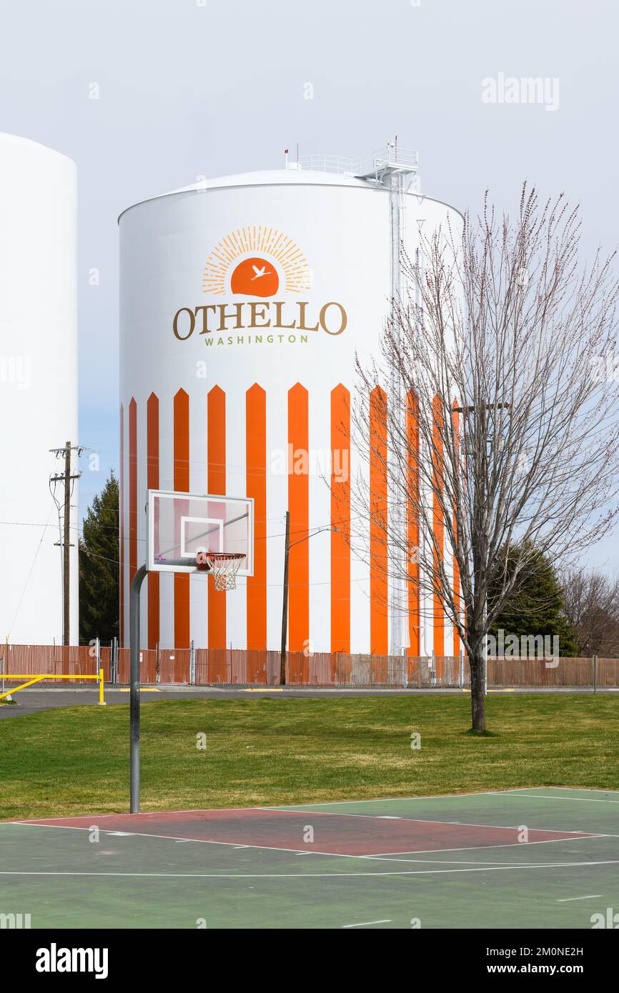 Othello, WA, USA - 24 marzo 2022; serbatoio dell'acqua Othello con nome e logo dietro il campo da pallacanestro Foto Stock