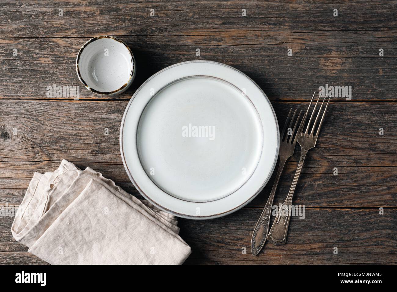 Piatto vuoto, argenteria vintage e biancheria tessile da cucina su vecchio tavolo di legno. Impostazione tabella rustica, vista dall'alto, spazio di copia per testo o elementi di disegno Foto Stock