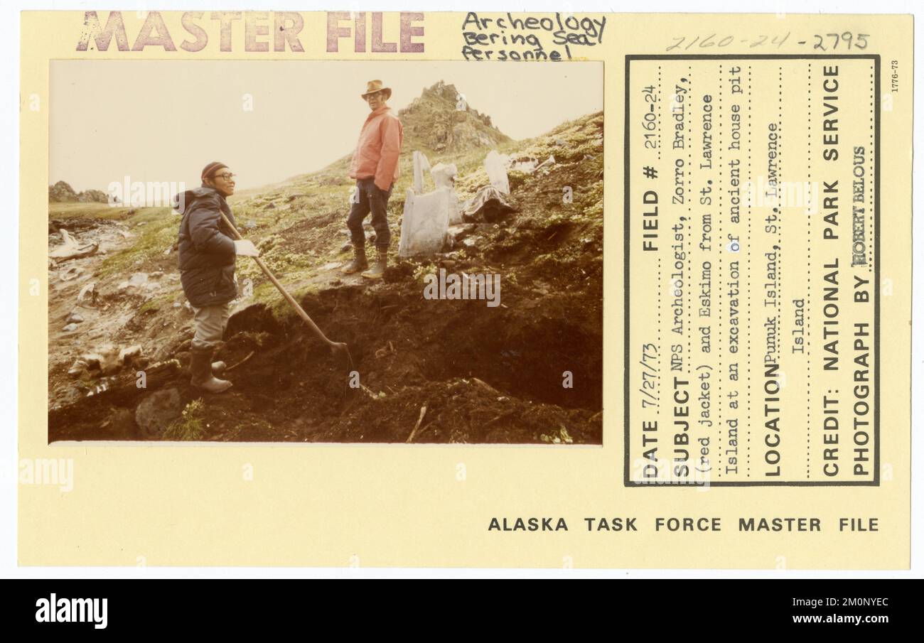 NPS archeologo Zorro Bradley (giacca rossa) e Eskimo da St Lawrence Island in uno scavo di antica casa buca. Alaska Task Force fotografie Foto Stock
