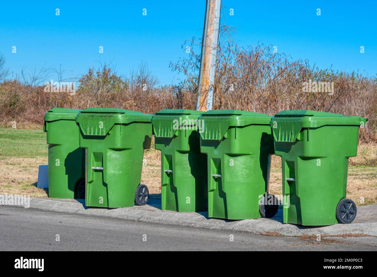 Cinque contenitori verdi di rifiuti residenziali per strada cittadina. Foto Stock