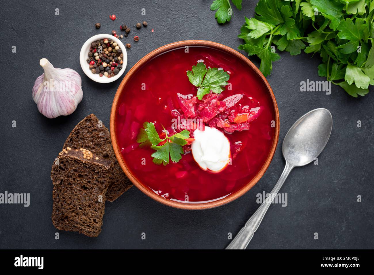 Borscht di barbabietola con panna acida, aglio e pane di segale su fondo in pietra nera. Vista dall'alto. Cibo di cultura ucraino Foto Stock