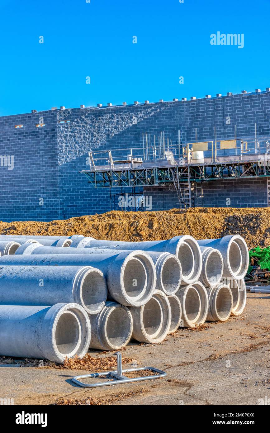 Immagine verticale di condotti in calcestruzzo e pareti in mattoni parzialmente costruite nel sito di costruzione di edifici per la vendita al dettaglio. Foto Stock