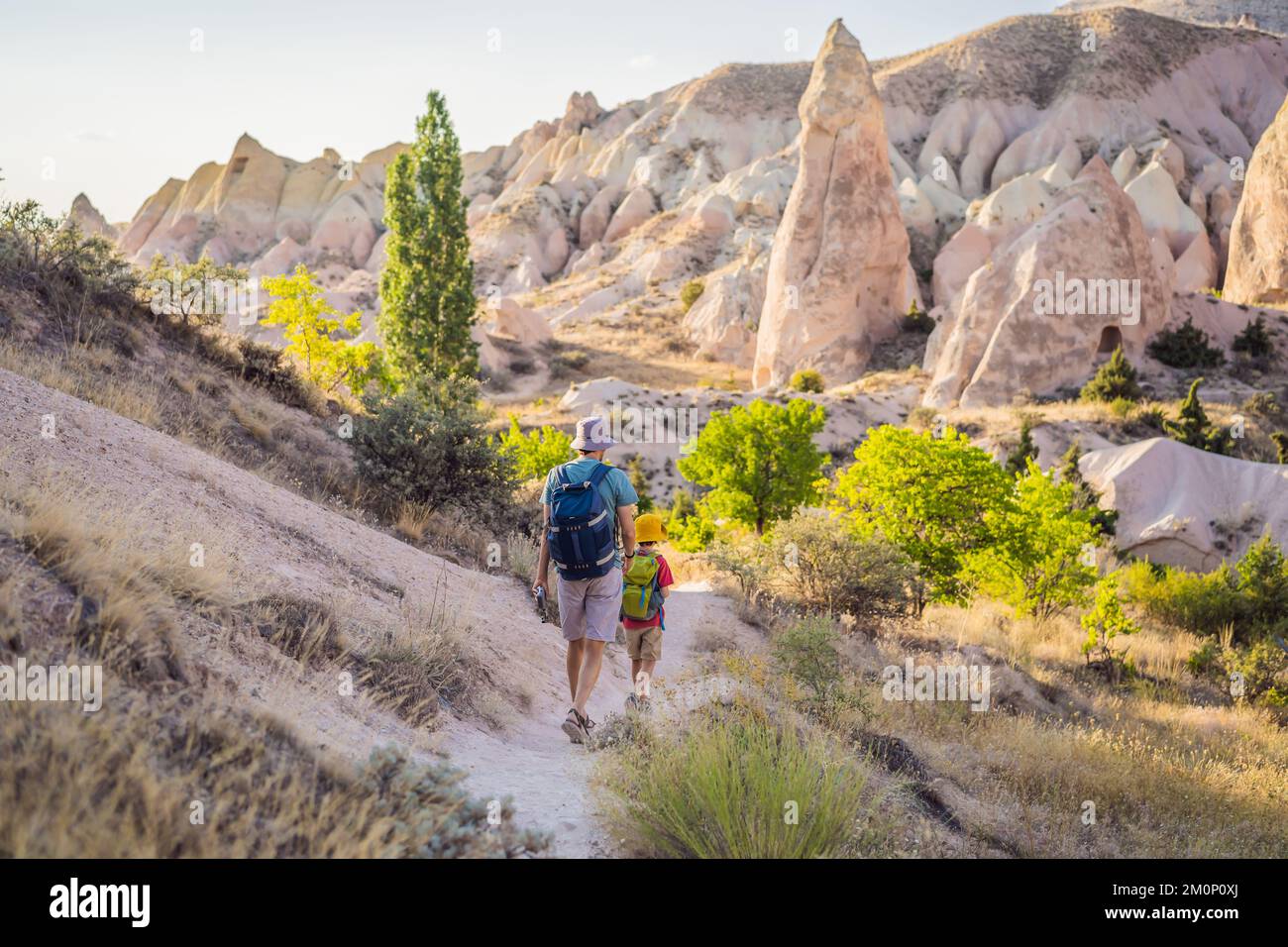Padre e figlio turisti esplorando la valle con formazioni rocciose e grotte delle fate vicino a Goreme in Cappadocia Turchia Foto Stock