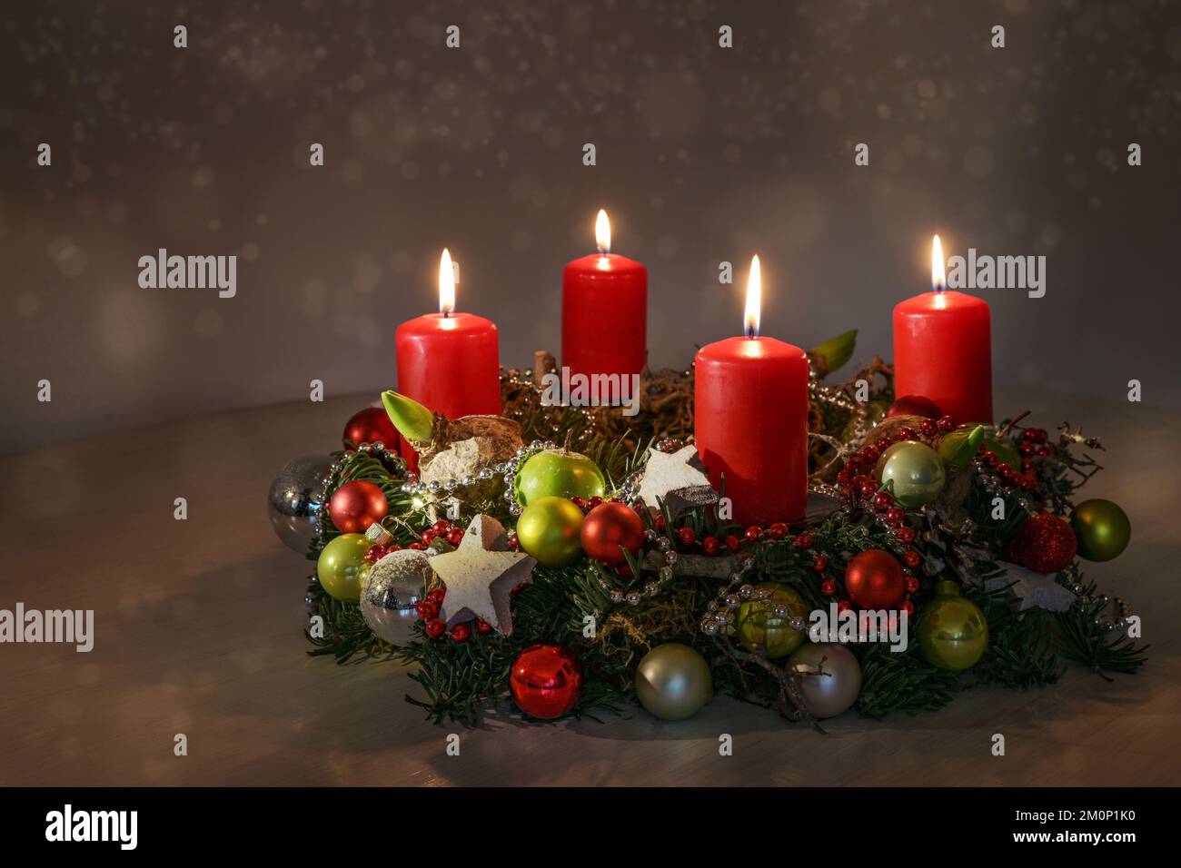 L'avvento rosso candele su una corona con decorazione di Natale contro uno sfondo caldo scuro con luci bokeh, spazio copia, messa a fuoco selezionata, profondità stretta di Foto Stock