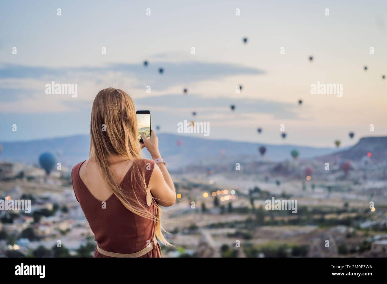 Donna turistica che guarda mongolfiere in Cappadocia, Turchia. Buon viaggio in Turchia concetto. Donna in cima a una montagna che gode di una vista meravigliosa Foto Stock