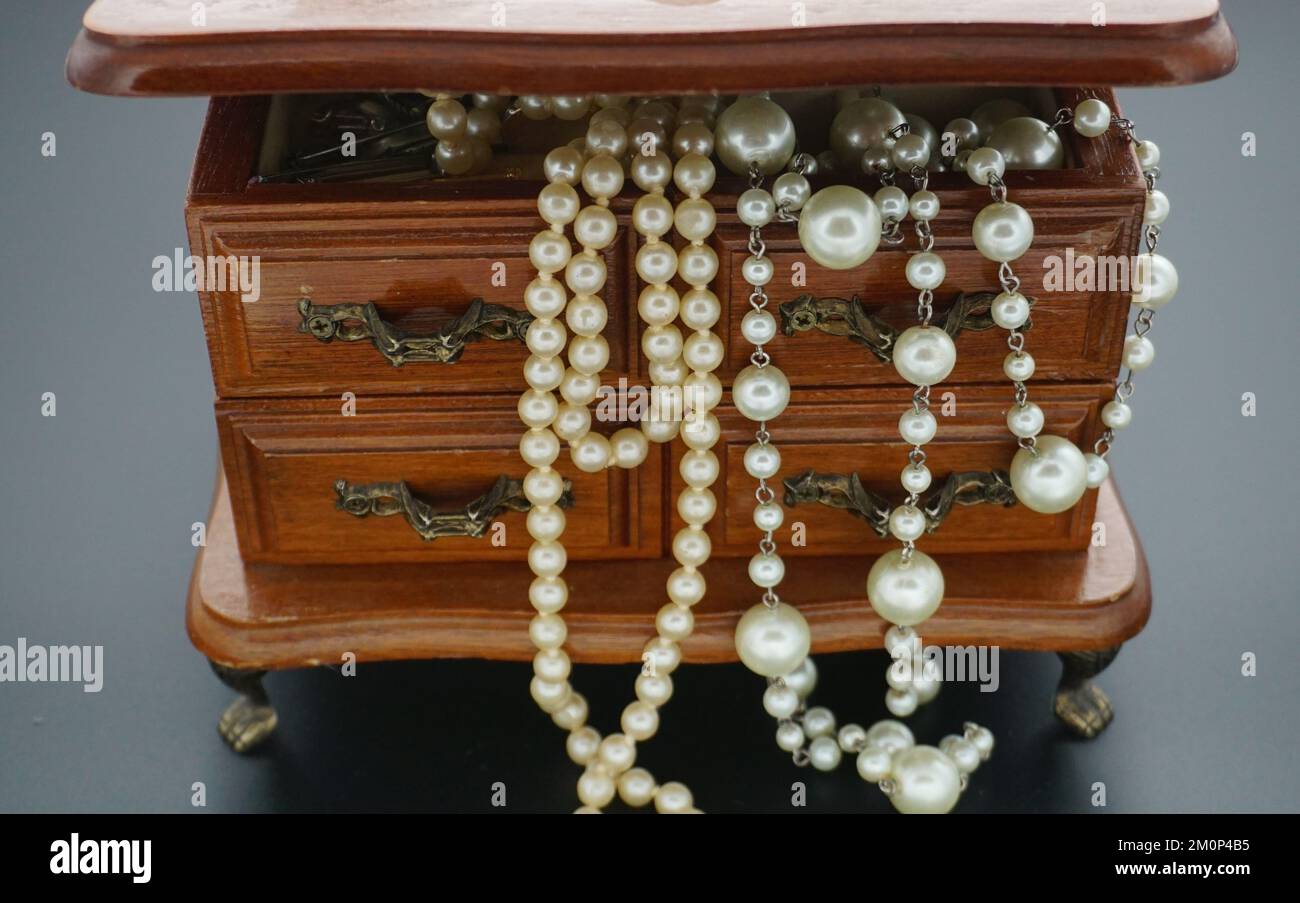 Un primo piano di collane extra lunghe in madreperla in un trinket vintage  in legno Foto stock - Alamy