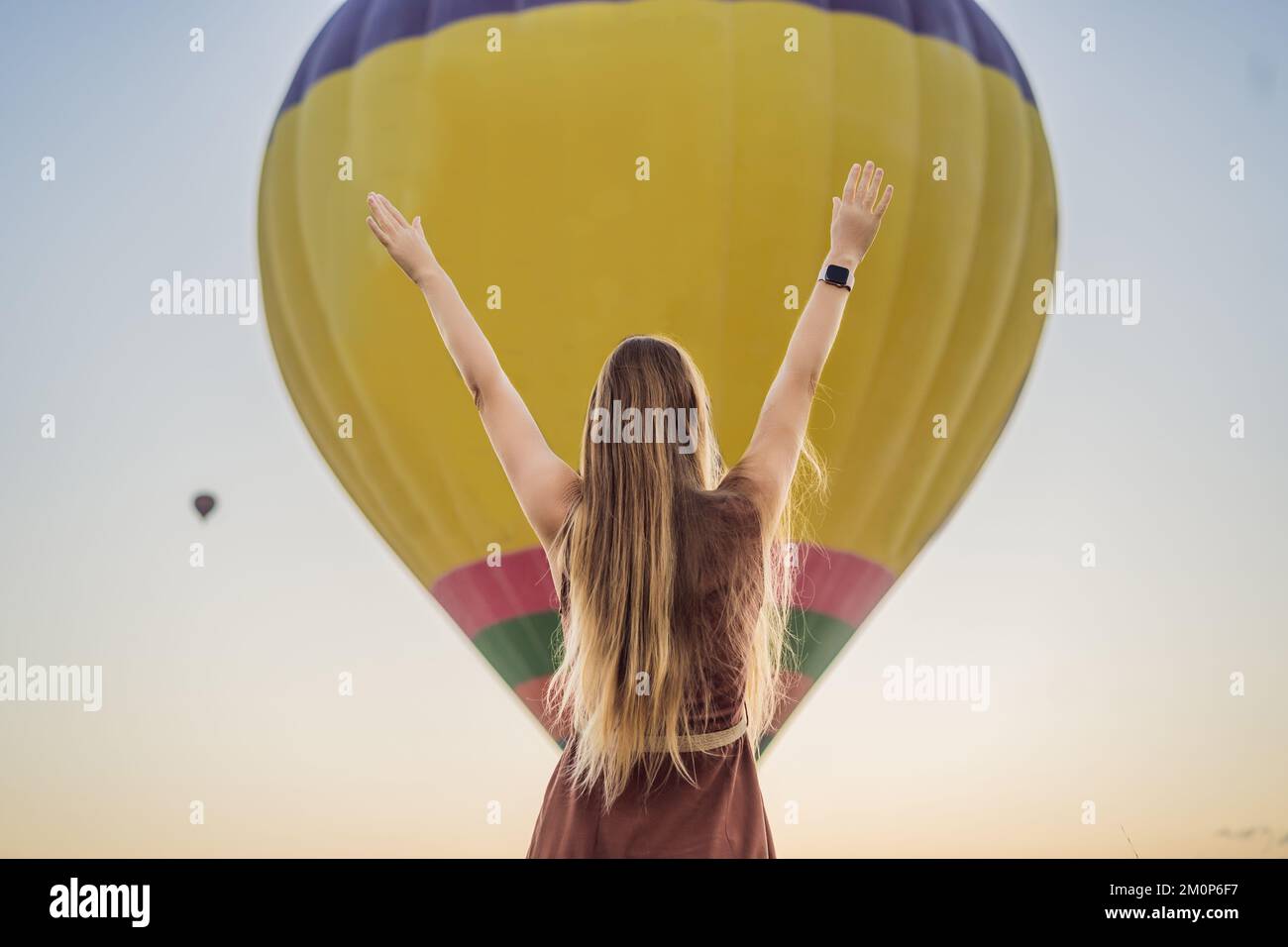 Donna turistica che guarda mongolfiere in Cappadocia, Turchia. Buon viaggio in Turchia concetto. Donna in cima a una montagna che gode di una vista meravigliosa Foto Stock