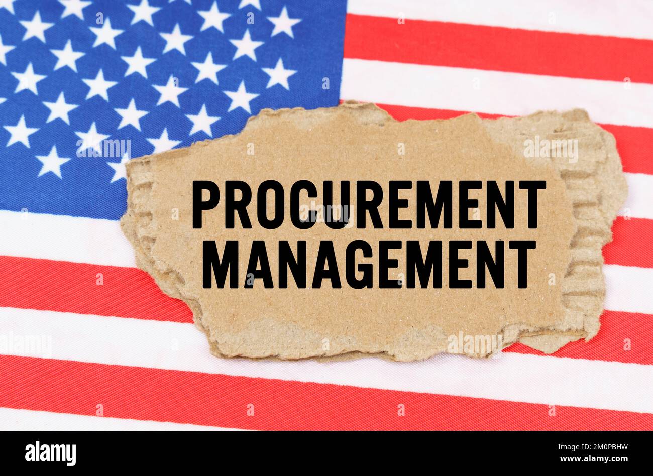 Concetto di business e finanza. Sulla bandiera degli Stati Uniti si trova una scatola di cartone con l'iscrizione - GESTIONE DEGLI APPALTI Foto Stock