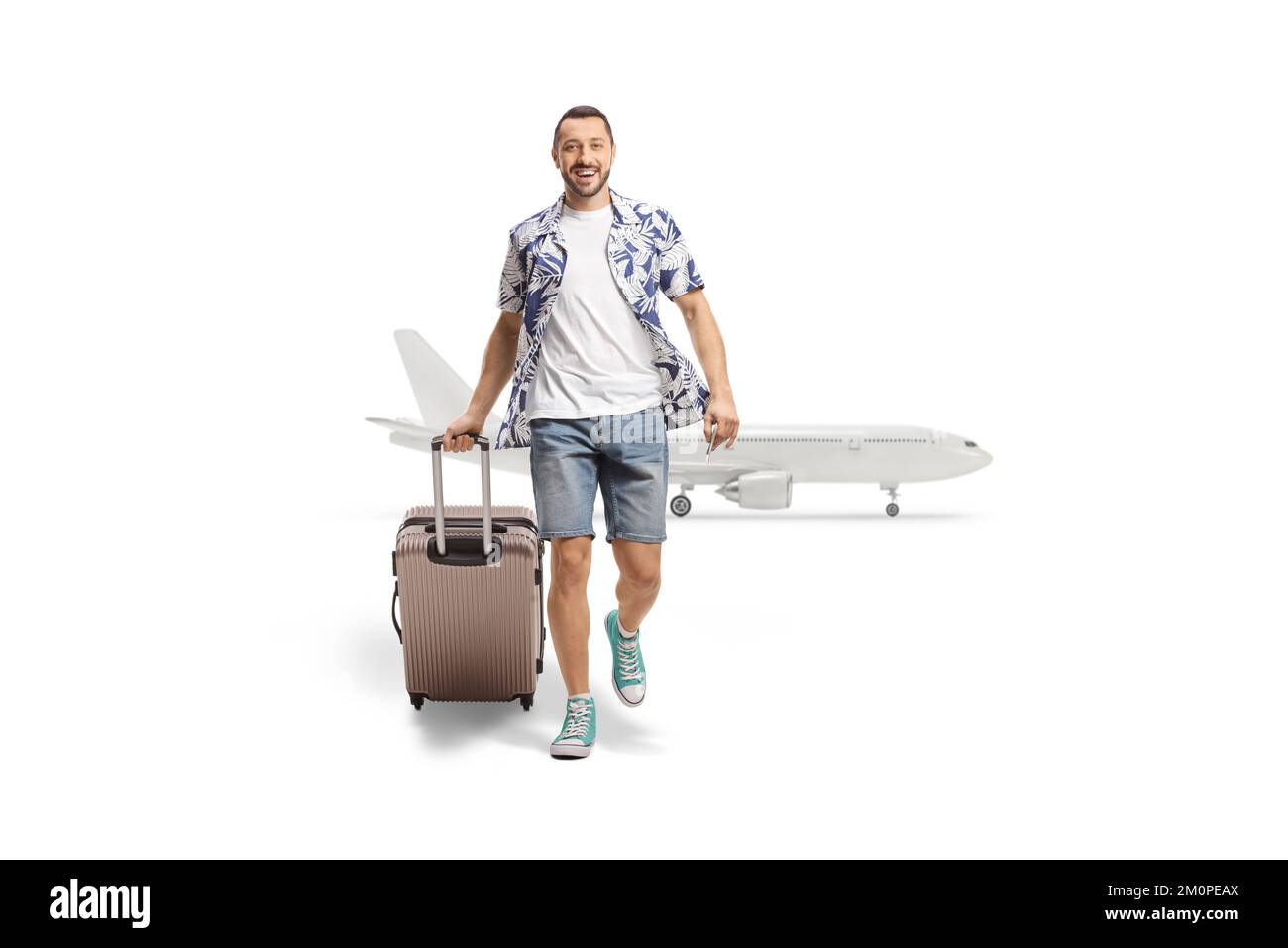 Ritratto a tutta lunghezza di un uomo sorridente proveniente da un aeroplano e che tira una valigia isolata su sfondo bianco Foto Stock