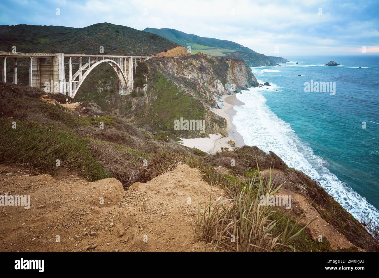 Big sur, California. Lo storico ponte Bixby, la costa rocciosa e l'Oceano Pacifico in una bella giornata nuvolosa Foto Stock