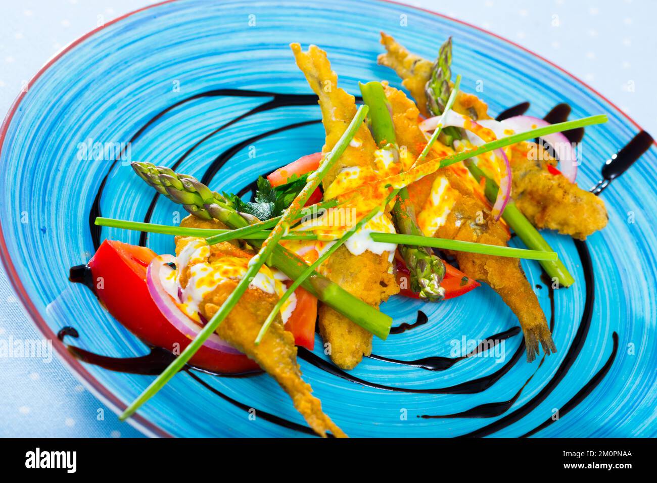 Sardine fritte in pastella con salsa di zenzero cremosa su un cuscino di pomodori dolci Foto Stock