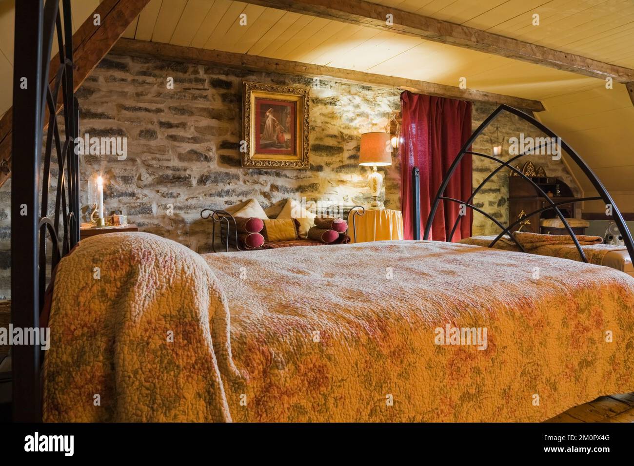 Letto matrimoniale ricoperto di motivi floreali, copriletto nella camera da letto principale al piano superiore, all'interno di una vecchia casa in pietra di campo in stile cottage canadese del 1850 circa. Foto Stock
