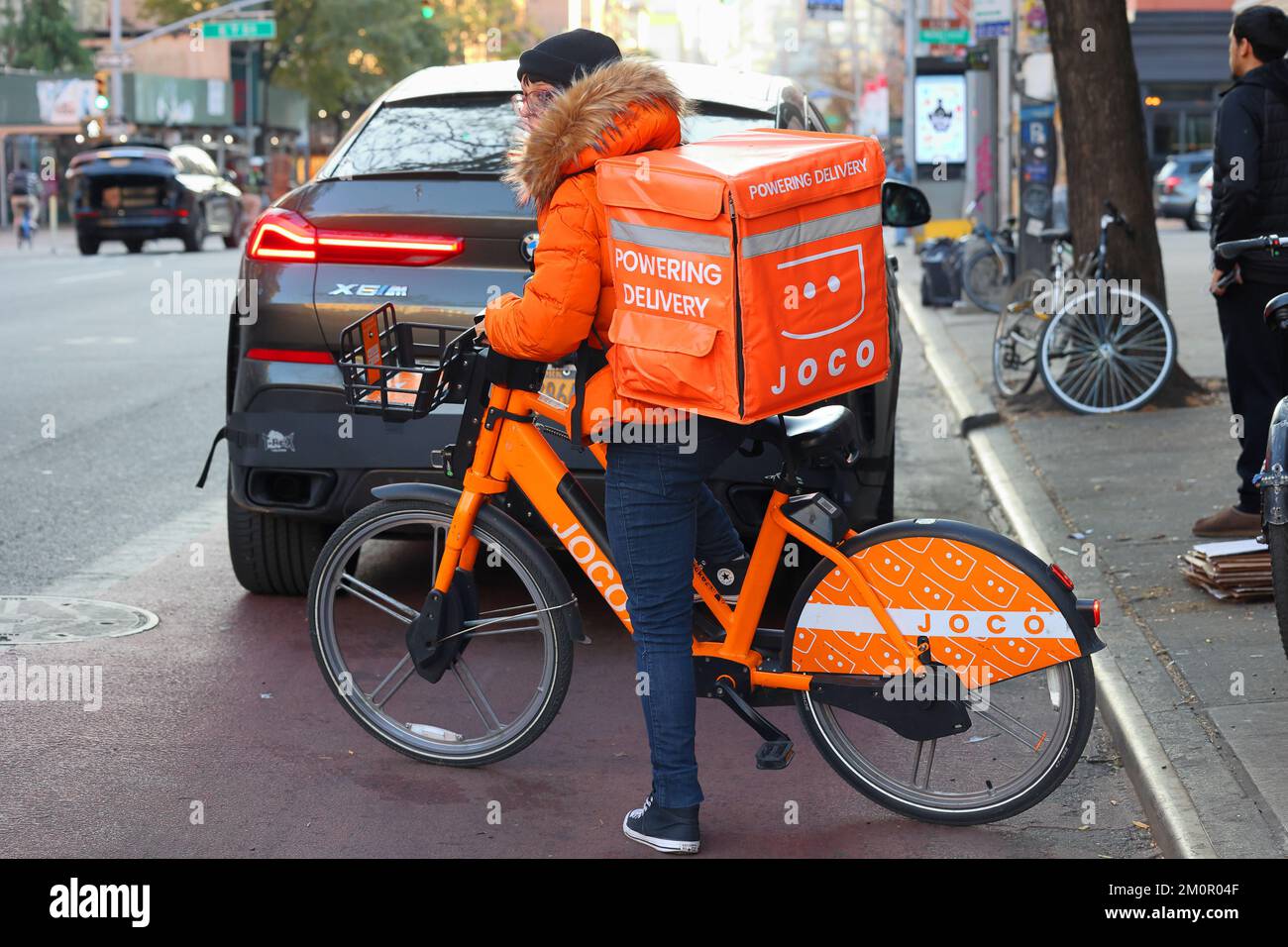 Una persona che consegna cibo su una bici elettrica JOCO a Manhattan. un lavoratore di concerto su una e-bike a noleggio Foto Stock