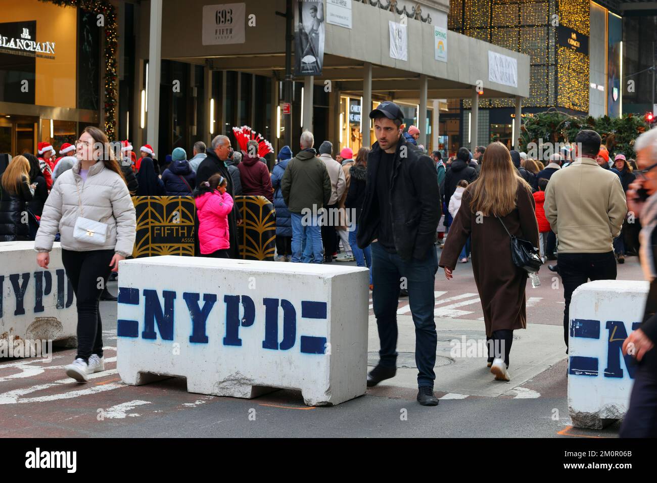 Persone che camminano attraverso una barriera di cemento NYPD per scoraggiare gli attacchi dei camion durante Open Streets Domenica sulla Fifth Ave, New York, 4 dicembre 2022. Foto Stock