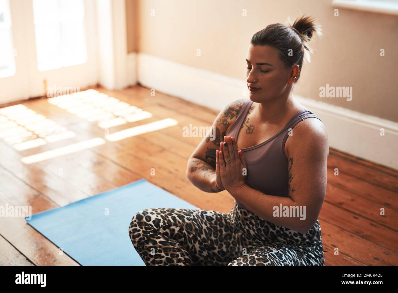 La meditazione fornisce un modo per imparare a lasciare andare. una giovane donna che medita su un tappetino yoga a casa. Foto Stock