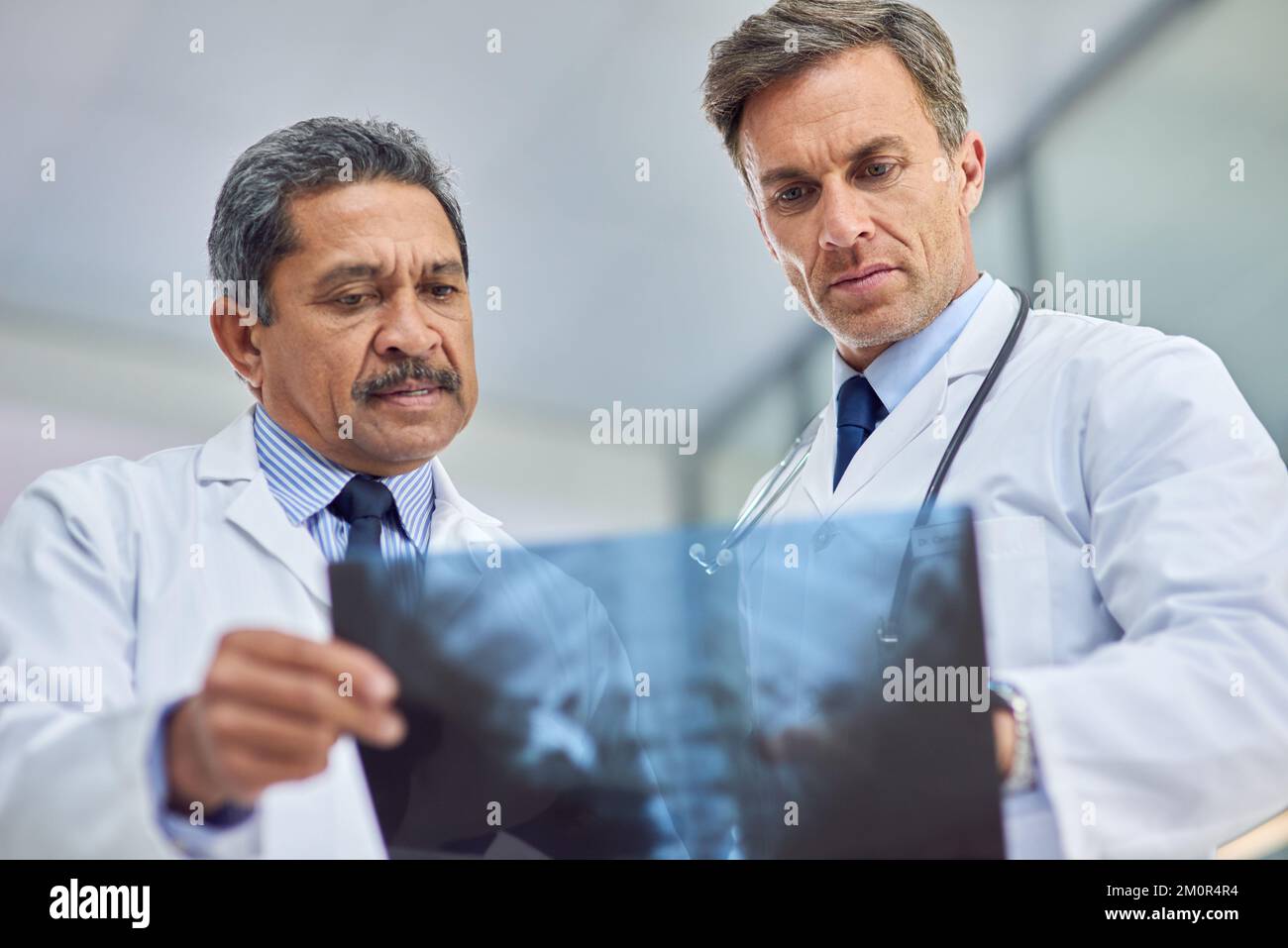 Consultare un collega per un secondo parere. due medici che osservano una radiografia insieme. Foto Stock
