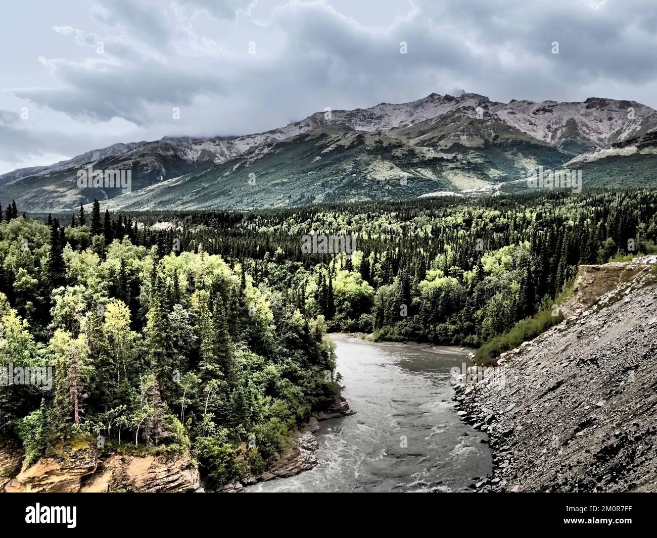 Alaska - fiume che attraversa la foresta, con una sporgenza rocciosa su un lato e montagne in lontananza, cielo cupo; manipolazione fotografica per effetto grafico Foto Stock