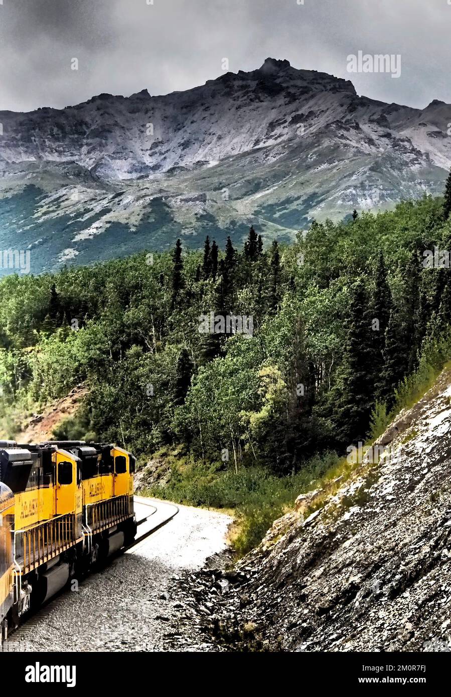 Alaska - treno giallo che arrotonda una curva, scendendo in montagna con la foresta; manipolazione fotografica per effetto grafico Foto Stock