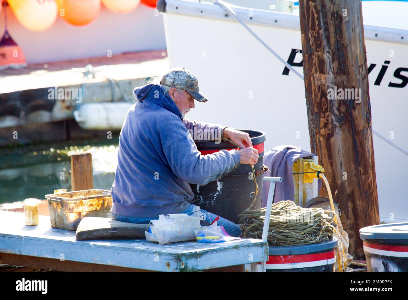 Fisherman seduto sul molo di preparazione Long Line Foto Stock