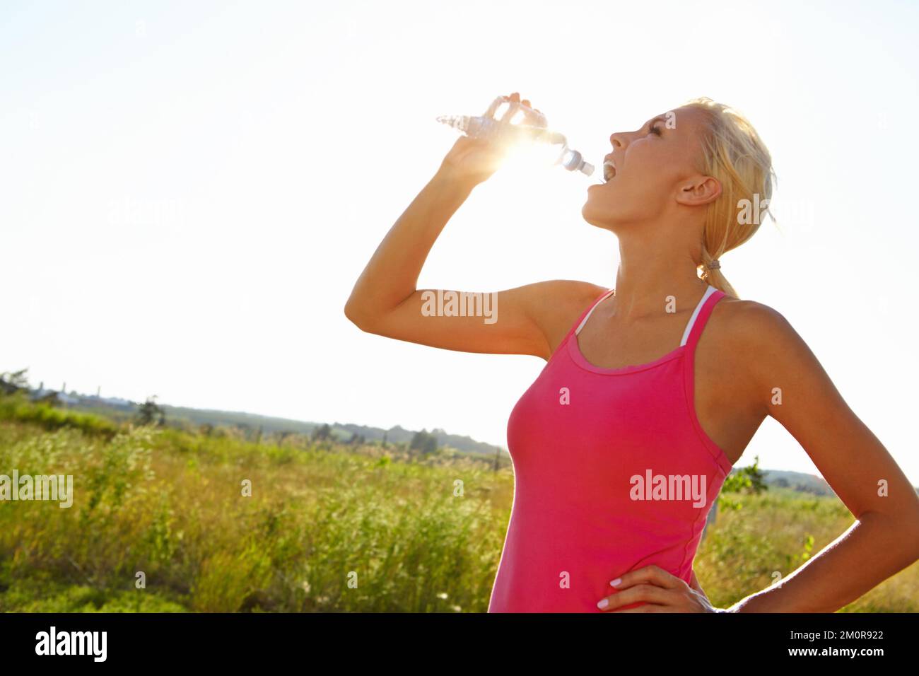 L'acqua è tutto ciò di cui ha bisogno. Una bella giovane donna in abbigliamento sportivo bere acqua da una bottiglia. Foto Stock