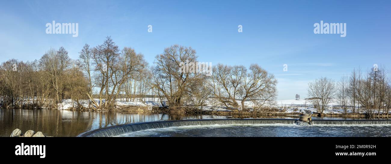 paesaggio invernale del fiume. parco con cascata ruscello tra il paesaggio innevato in una giornata di sole. foto panoramica. Foto Stock