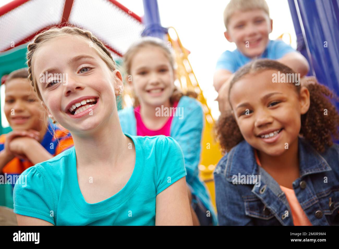 Domani le speranze e i sogni riposano su di loro. Un gruppo multietnico di bambini felici che giocano in una palestra nella giungla in un parco giochi. Foto Stock