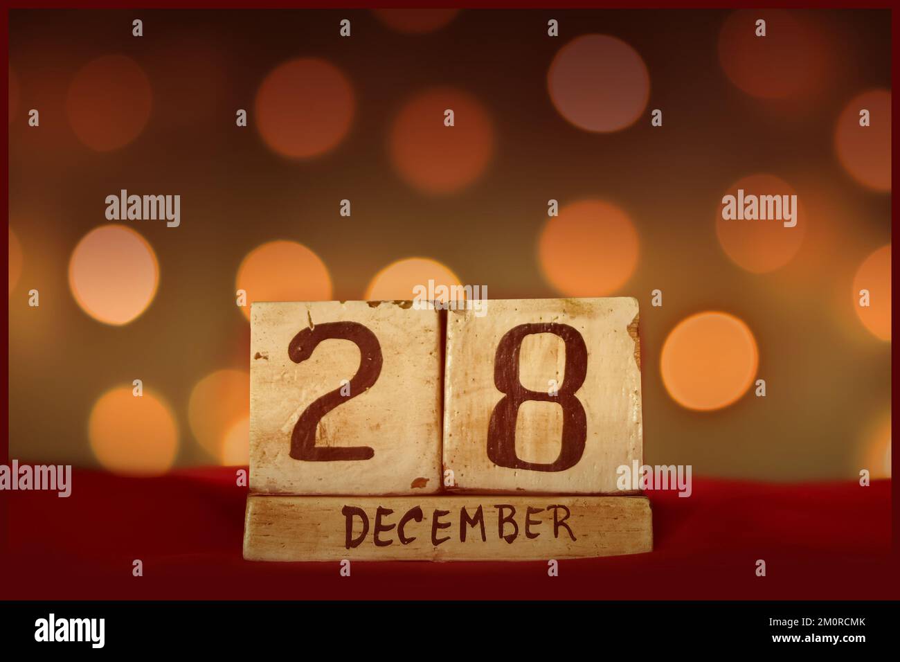 Dicembre 28 calendario in legno blocco vintage su tessuto rosso, festive bokeh luci sfondo biglietto di auguri festeggiando le vacanze, compleanno, salvare la data f Foto Stock