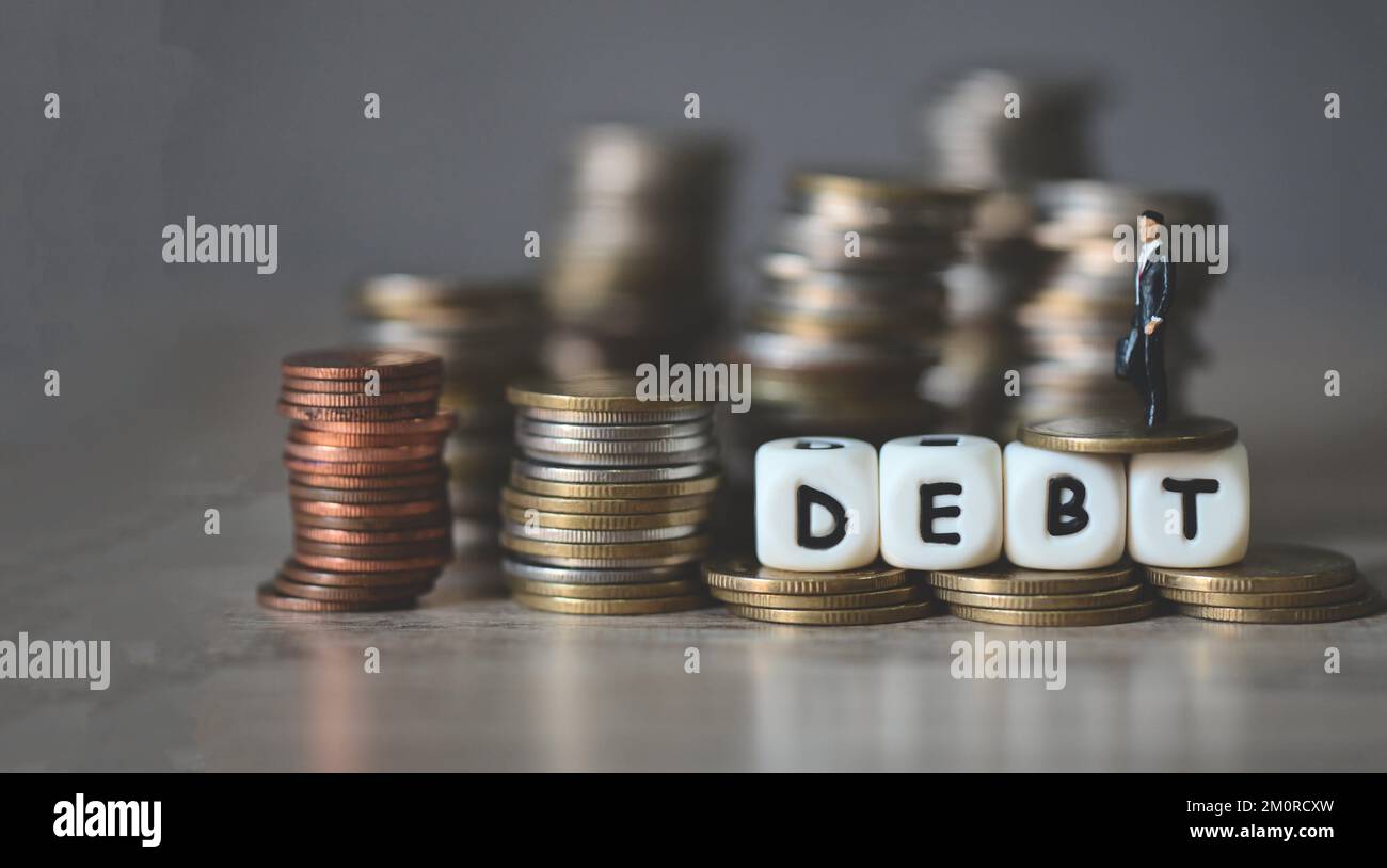 Debito economia di affari di denaro e finanza parola debito su monete con uomo d'affari, pagamento delle tasse e del debito allo stato, concetto di finanziario Foto Stock