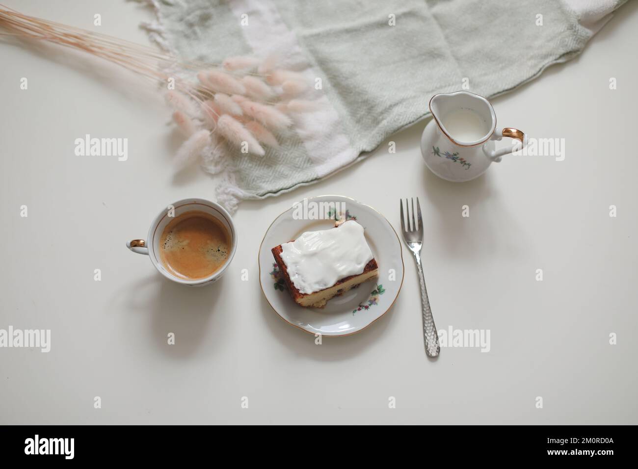 colazione con una tazza di caffè e una brocca di latte su uno sfondo di legno bianco, primo piano. Colazione energetica, concetto di routine mattutina Foto Stock