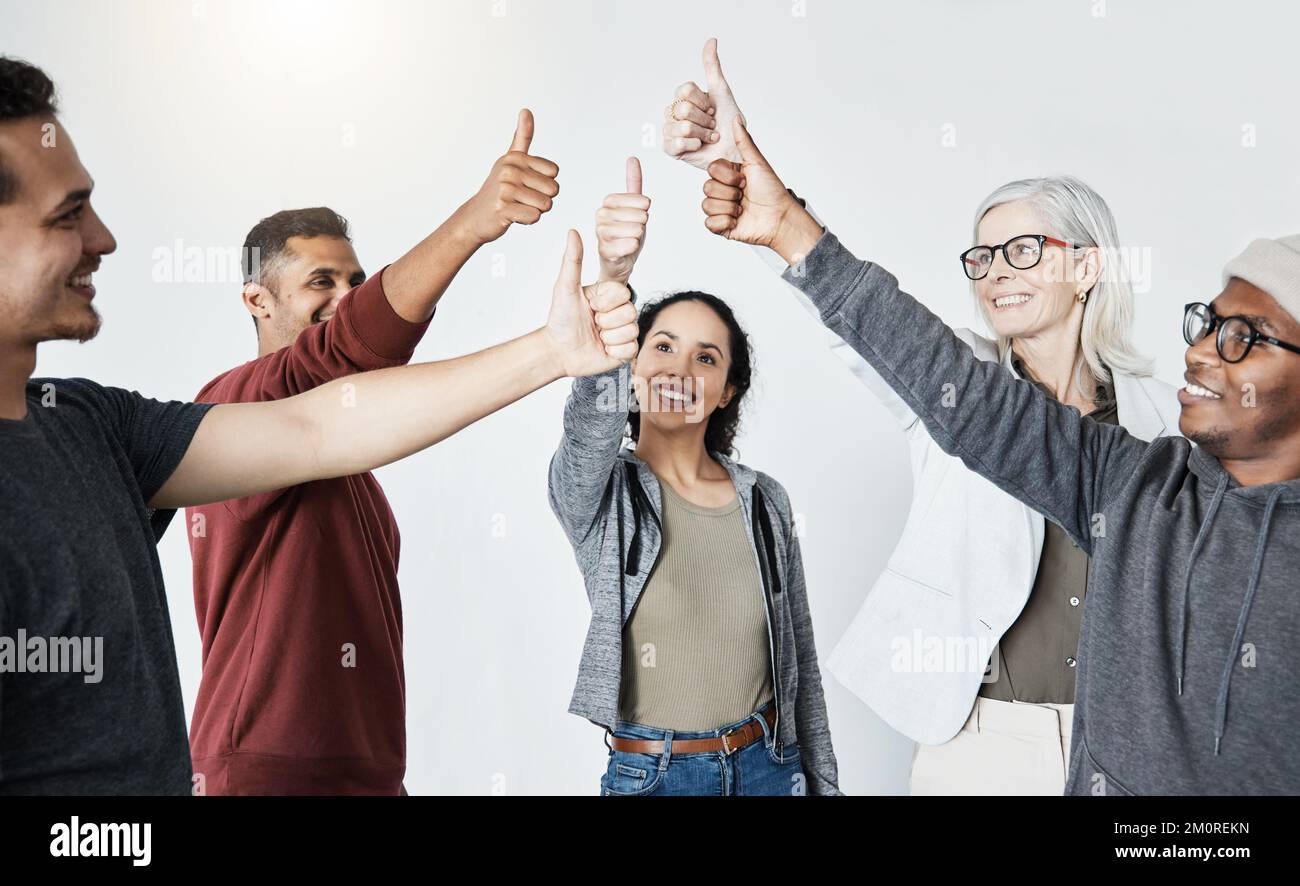Gruppo felice di diversi uomini d'affari mostrando un pollice in piedi insieme in una riunione in un ufficio al lavoro. Uomini e donne sorridenti e che sorreggono un Foto Stock