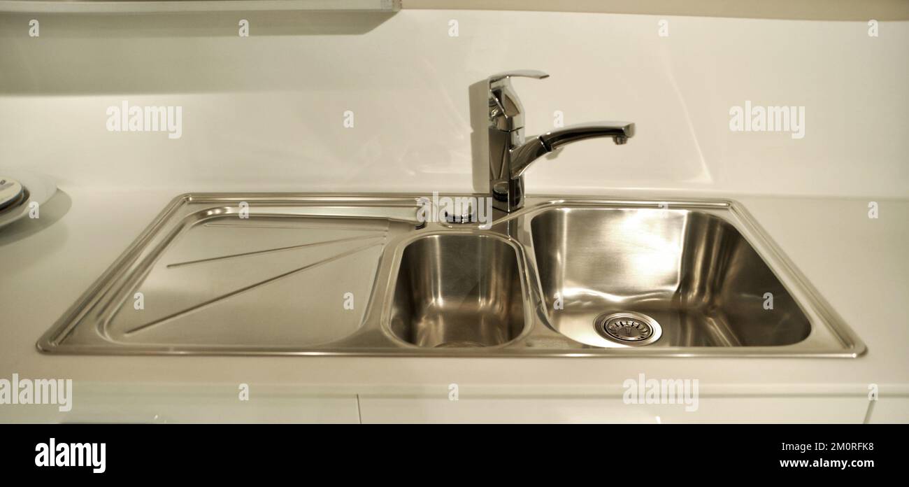 Interno di lussuosa cucina moderna e lavandino, rubinetto e scarico in acciaio inossidabile Foto Stock