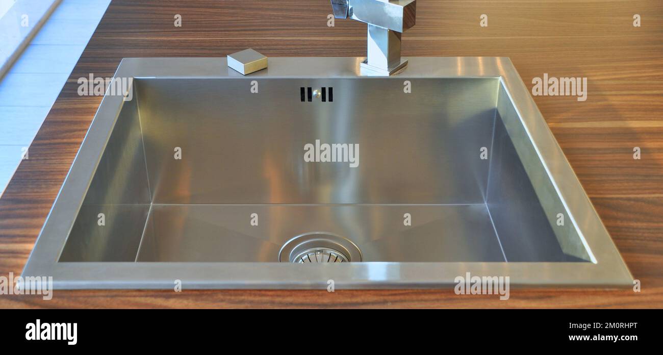 Interno di lussuosa cucina moderna e lavandino, rubinetto e scarico in acciaio inossidabile Foto Stock