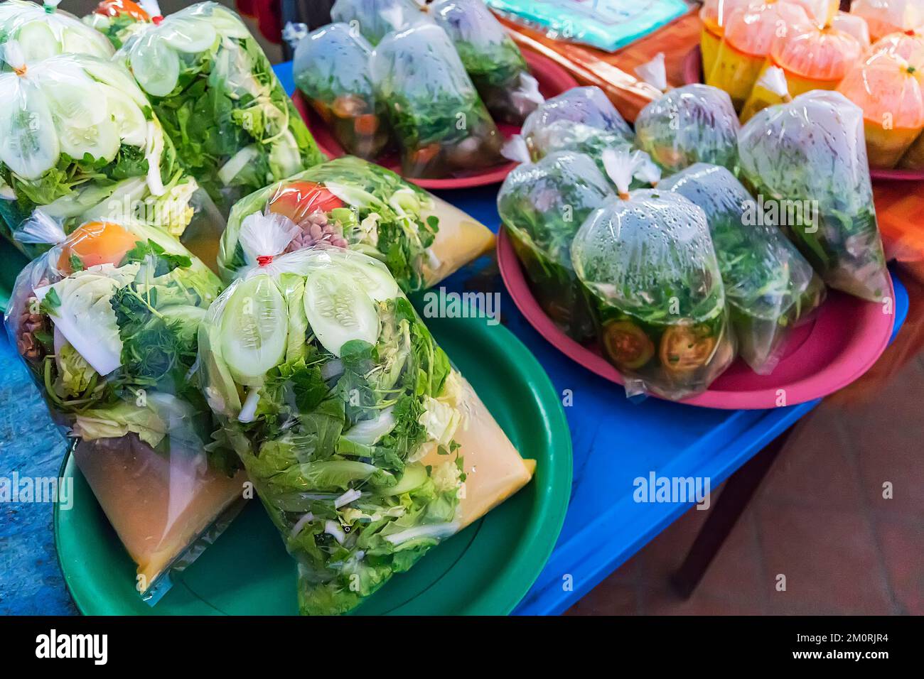 Tradizionale zuppa tailandese e il curry in borse di plastica in un vassoio di metallo in un mercato di strada, vicino, Thailandia. Thai street food in una busta di plastica, cucina thai Foto Stock