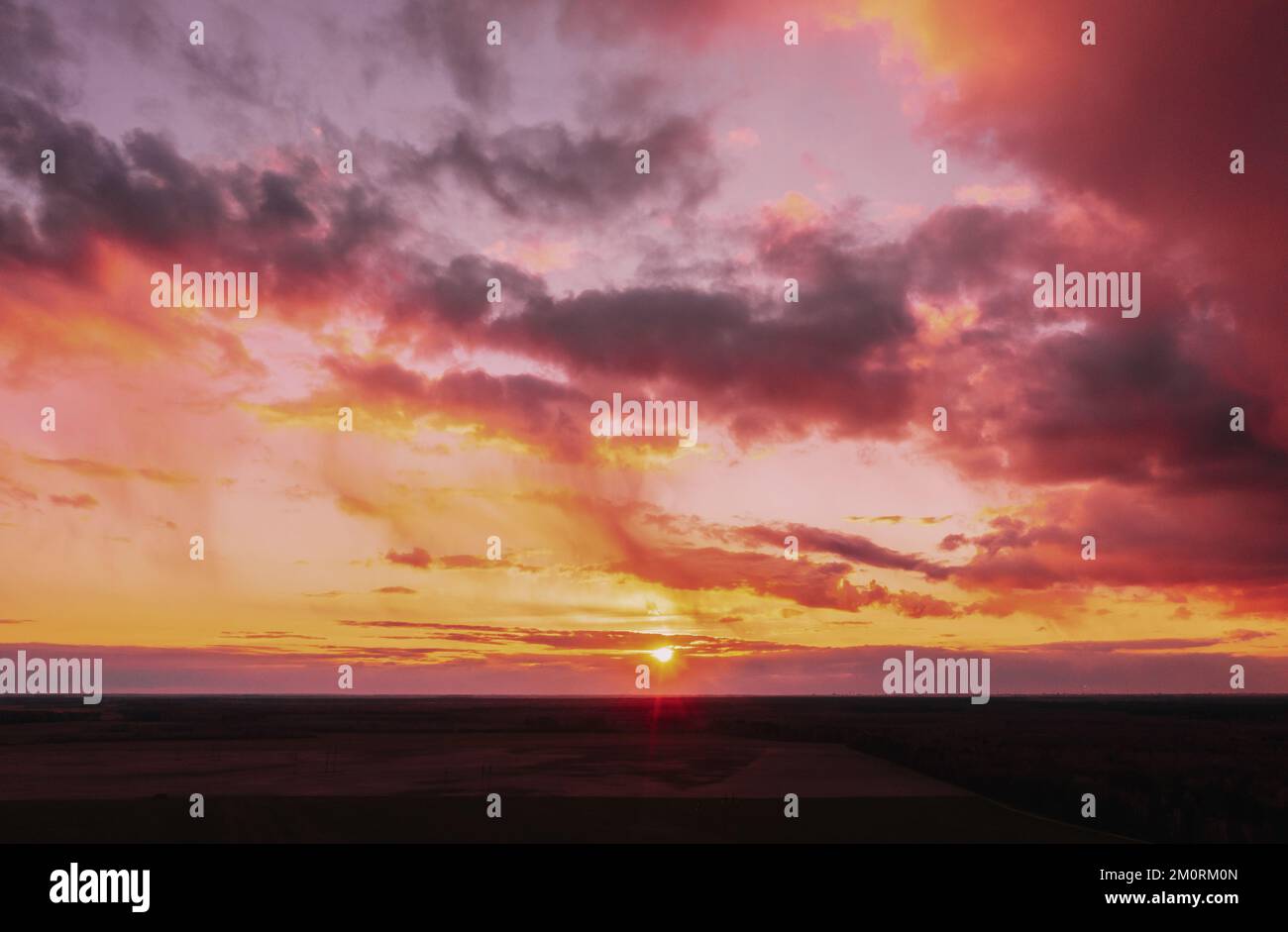 Tramonto alba cielo colorato su campo o prato. Cielo luminoso e drammatico e terreno scuro. Paesaggio di campagna sotto paesaggistico incredibile naturale luminoso Foto Stock